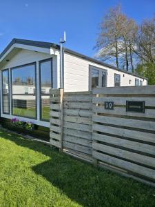 a tiny house with a fence in the grass at PRACHTiG CHALET ZONNESTRAAL in Westerland