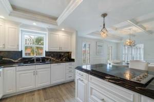 a kitchen with white cabinets and a black counter top at Three Bedroom Gulffront Condo with Sunset Views in Naples