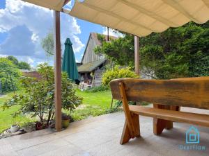 a wooden bench sitting on a porch under an umbrella at NaWypasie Grand Apartment with Fireplace Beautiful Garden SUP Board and Just 30 Minutes from Gdańsk and Gdynia in Szemud