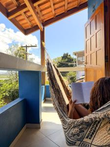 a woman laying in a hammock reading a book at Casa Magna in Itacaré