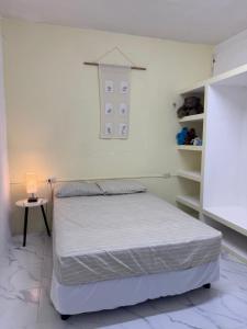 a white bedroom with a bed and a small table at Casa verde El Platanar con Jardín Tropical Calkiní in Calkiní
