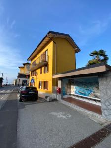 a yellow building with a car parked in front of it at Around Lago Maggiore apartments in Reno Di Leggiuno