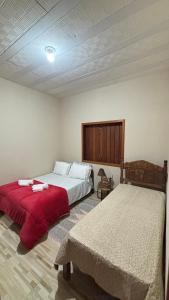 a bedroom with two beds and a red blanket at Alto do Paraíso Bichinho in Prados