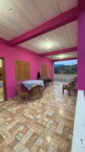 a room with purple walls and a table and chairs at Alto do Paraíso Bichinho in Prados