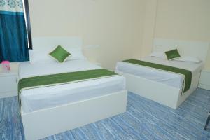 two beds in a small room withthritisthritis at Vetri Residency in Agastīswaram