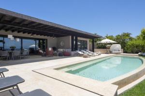 a swimming pool with a patio and a house at Porta Fortuna Villa Punta Mita Gates in Punta Mita
