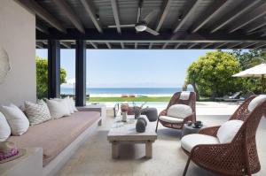 a living room with a couch and chairs and the ocean at Porta Fortuna Villa Punta Mita Gates in Punta Mita
