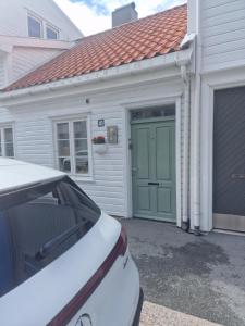 a garage with a green door and a car parked in front at Sommerbolig i byen in Kristiansand