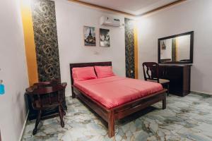 ein Schlafzimmer mit einem Bett mit roten Laken und einem Stuhl in der Unterkunft La clémentine in Jacqueville