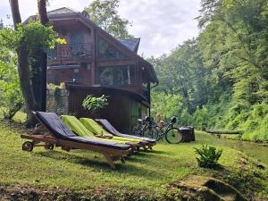 a house with two lounge chairs in the grass at Kuća za odmor uz rijeku Slapnica, u Parku prirode Žumberak, finska sauna i jacuzzi in Krašić