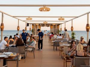 a restaurant on the beach with people sitting at tables at Alaçatı Beach Resort in Yumru