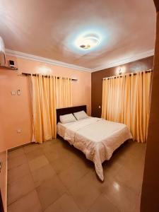 a bedroom with a large bed with yellow curtains at Seyi Homes in Hausa