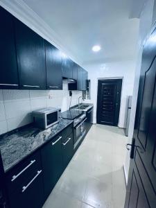 a kitchen with black cabinets and a microwave at Seyi Homes in Hausa