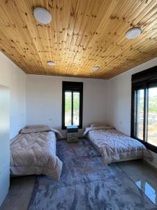 two beds in a room with a wooden ceiling at زهرة الخليج in Jerash