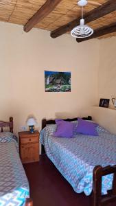 a bedroom with two beds and a table with a lamp at Hostería el Sol Naciente in Tilcara