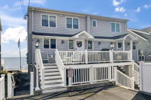 a house with a white fence in front of the ocean at Sunrise Waterfront Retreat in Milford