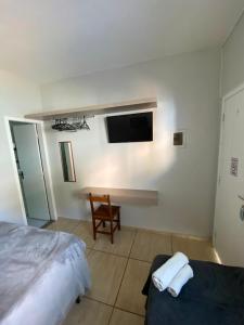 a bedroom with a bed and a tv on the wall at Suítes Água Marinha in Cabo Frio