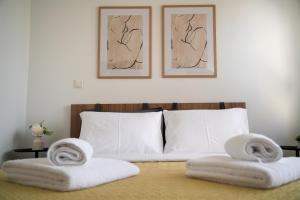 a bedroom with white towels on a bed with two pictures at Meltemi by GG in Alexandroupoli
