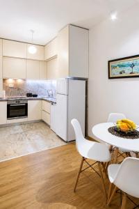 a white kitchen with a table and chairs at Modern New Apartment Miss T I Free Parking I Great Location in Podgorica