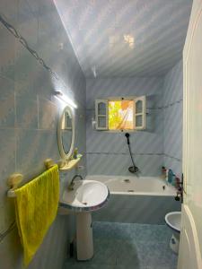 a bathroom with a sink and a tub and a mirror at Vacation home in Kelibia