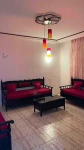 a living room with two red beds and a table at Vacation home in Kelibia