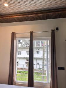 a window with curtains in a bedroom with a building at Rodali stay in Dibrugarh