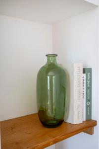 a green glass vase sitting on a shelf next to a book at Oltre i coni in Santa Lucia