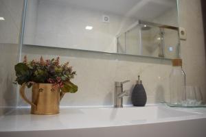 a bathroom sink with a vase of flowers on it at Alojamento Madeira`s in Videmonte +15 photos
