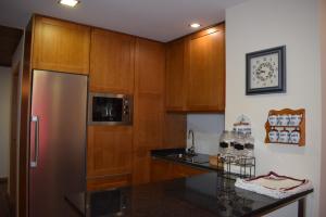 a kitchen with wooden cabinets and a stainless steel refrigerator at Alojamento Madeira`s in Videmonte