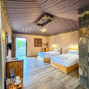 two beds in a large room with a wooden ceiling at Jebel Shams Resort منتجع جبل شمس in Dār Sawdāʼ +66 photos