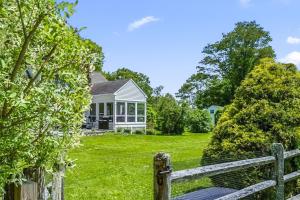 a white house with a fence in front of a yard at Bluestone Cottage in Goshen
