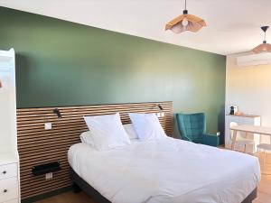 a bedroom with a white bed with a green wall at Claïla Appart-Hôtel Abzac in Abzac