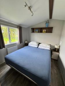 a bedroom with a large blue bed with two pillows at Prachtig chalet DE WADLOPER in Westerland