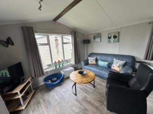a living room with a blue couch and a table at Prachtig chalet DE WADLOPER in Westerland
