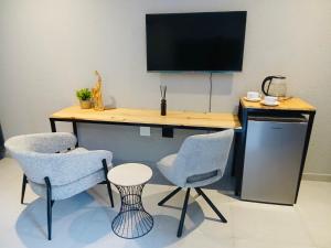 a desk with two chairs and a television on a wall at Gold Pepper Boutique Guesthouse in Siyabuswa +5 photos