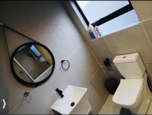 a bathroom with a toilet and a mirror and a sink at Gold Pepper Boutique Guesthouse in Siyabuswa