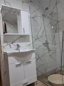 a white bathroom with a sink and a mirror at Suvi Vrh mountain cabin in Gacko