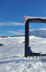 a child sitting in the snow under a sign at Suvi Vrh mountain cabin in Gacko