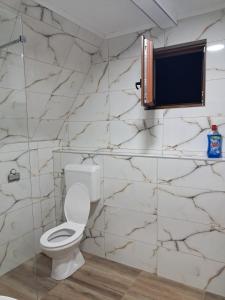 a bathroom with a toilet and a marble wall at Suvi Vrh mountain cabin in Gacko