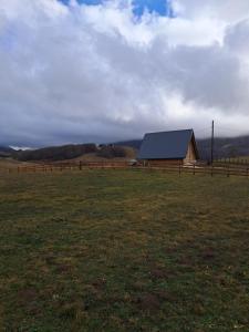a barn in a field next to a fence at Suvi Vrh mountain cabin in Gacko