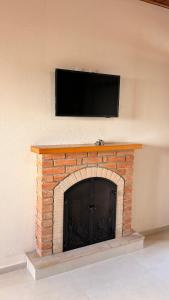 a brick fireplace with a flat screen tv above it at Chalés Nascer do Sol in Camanducaia