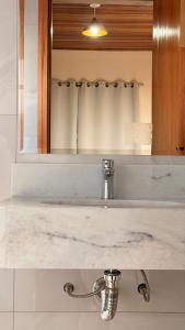 a bathroom counter with a sink and a mirror at Chalés Nascer do Sol in Camanducaia