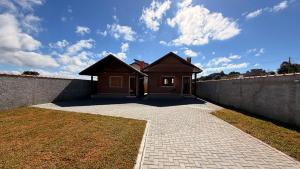 a house with a brick driveway in front of a wall at Chalés Nascer do Sol in Camanducaia