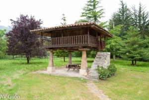 a wooden gazebo with a bench in a park at La Xana de Peón AVG in Candanal