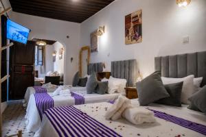 a hotel room with three beds and a television at Riad Al Fanouss in Fez
