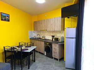 a kitchen with yellow walls and a table and a refrigerator at CityHaven in Ureki