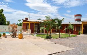 a yellow house with palm trees and a water tower at Pousada Neca Raabe in Pântano Grande