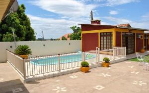 a house with a swimming pool next to a fence at Pousada Neca Raabe in Pântano Grande