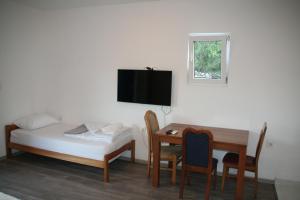 a small room with a bed and a table and a desk at B-I Apartmani in Glavatske Kućice