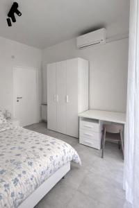 a white bedroom with a bed and a desk at Venera Rooms in Caltanissetta